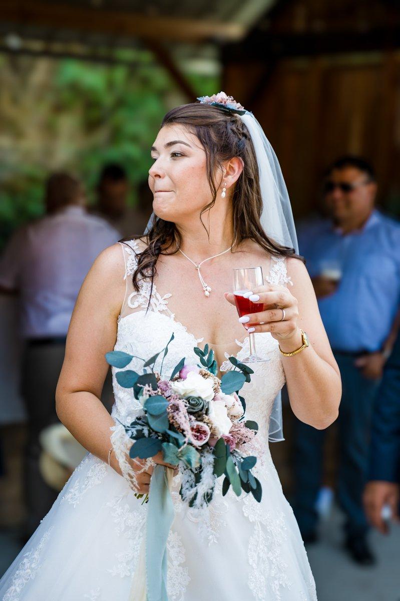Mariée tenant son bouquet et son verre au vin d'honneur