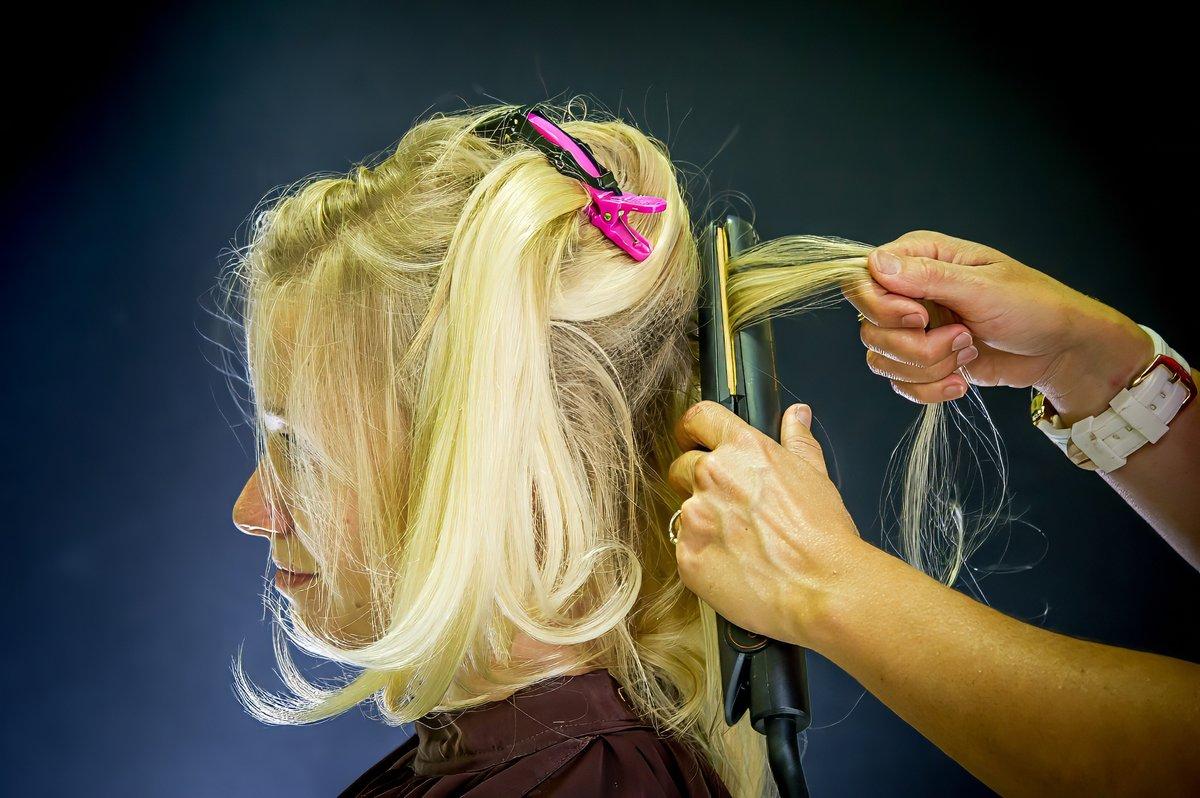 Coiffeuse lissant les cheveux de la mariée