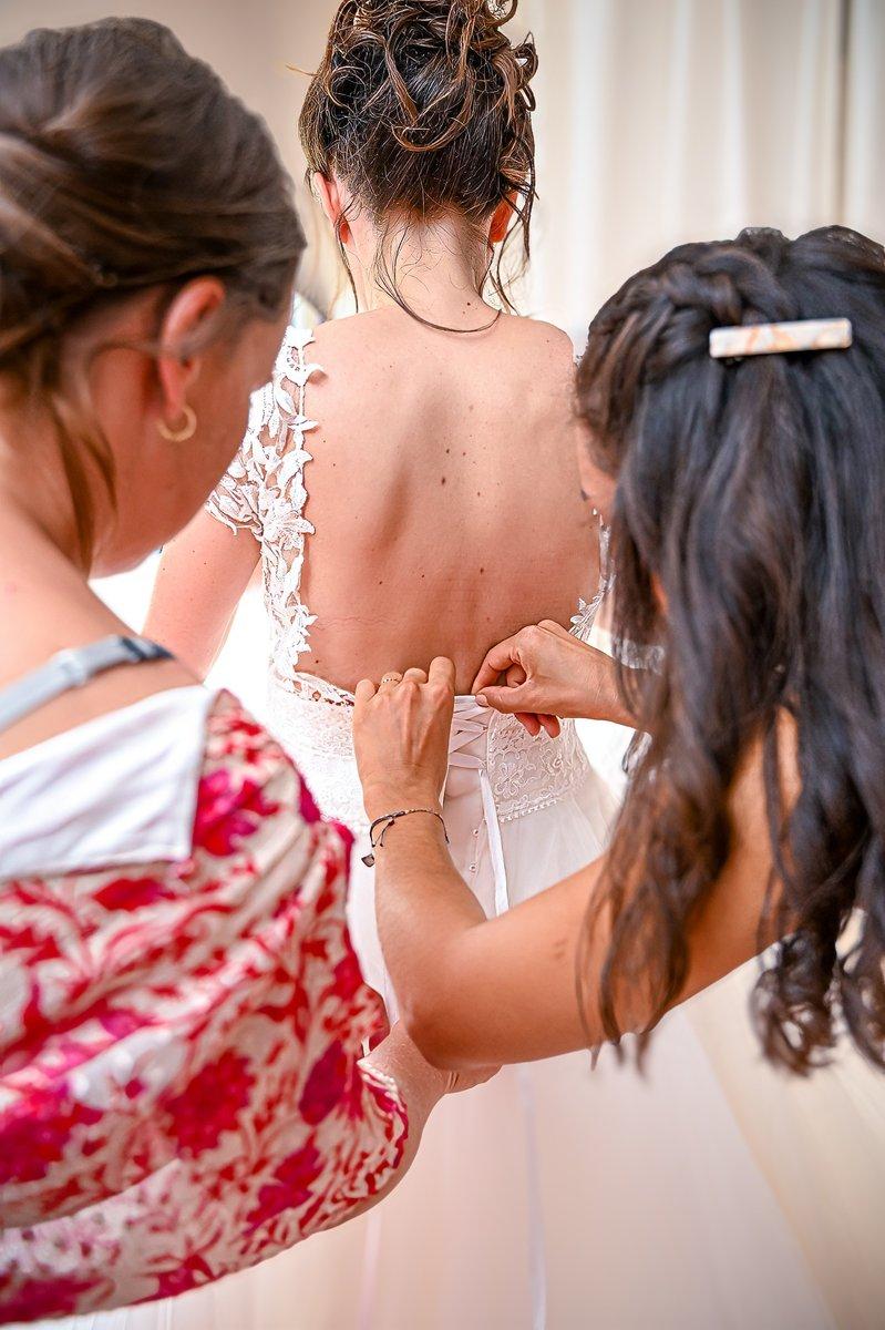 Deux femmes ajustant le dos de la robe de mariée
