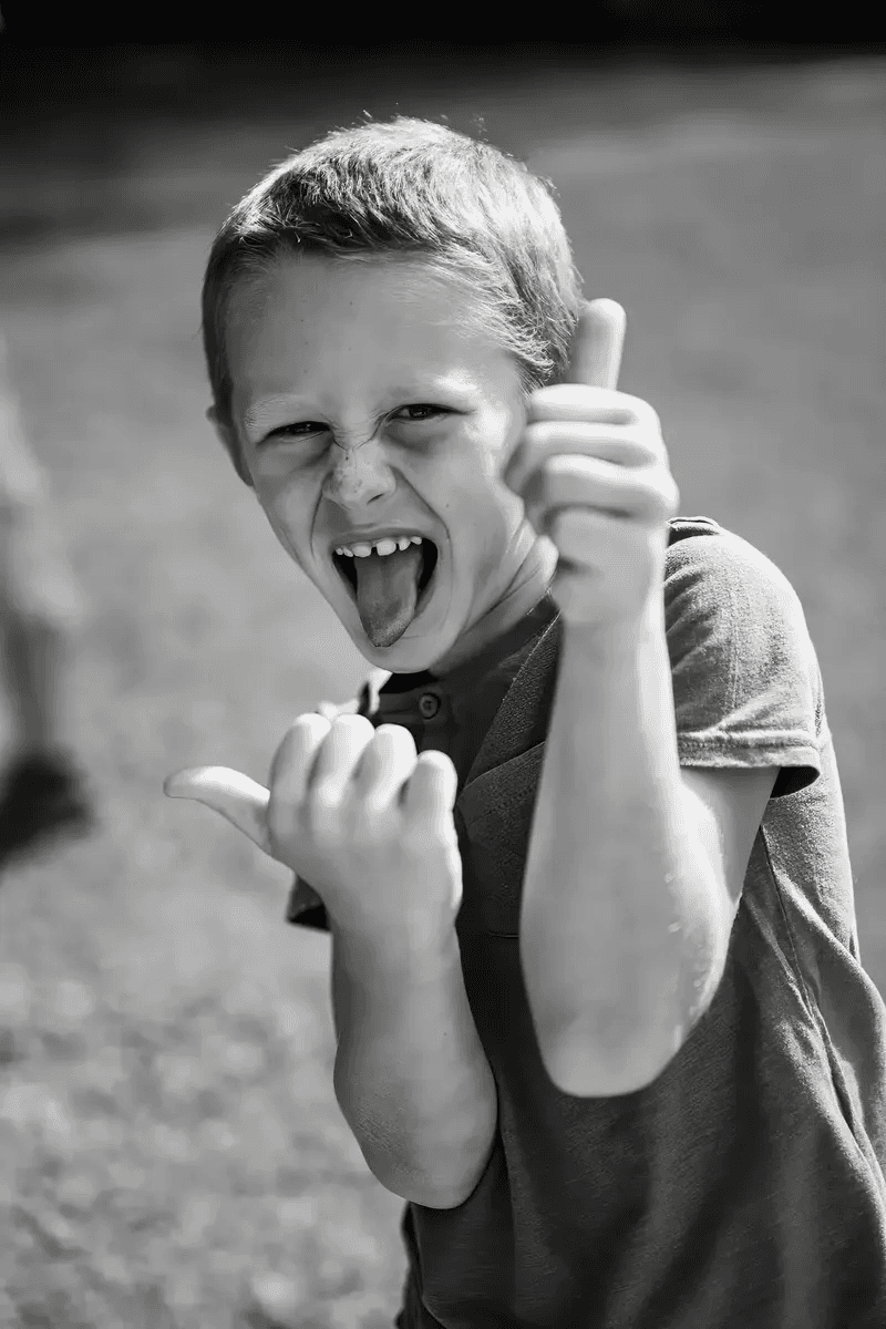 Enfant faisant des grimaces amusantes avec les mains et tirant la langue