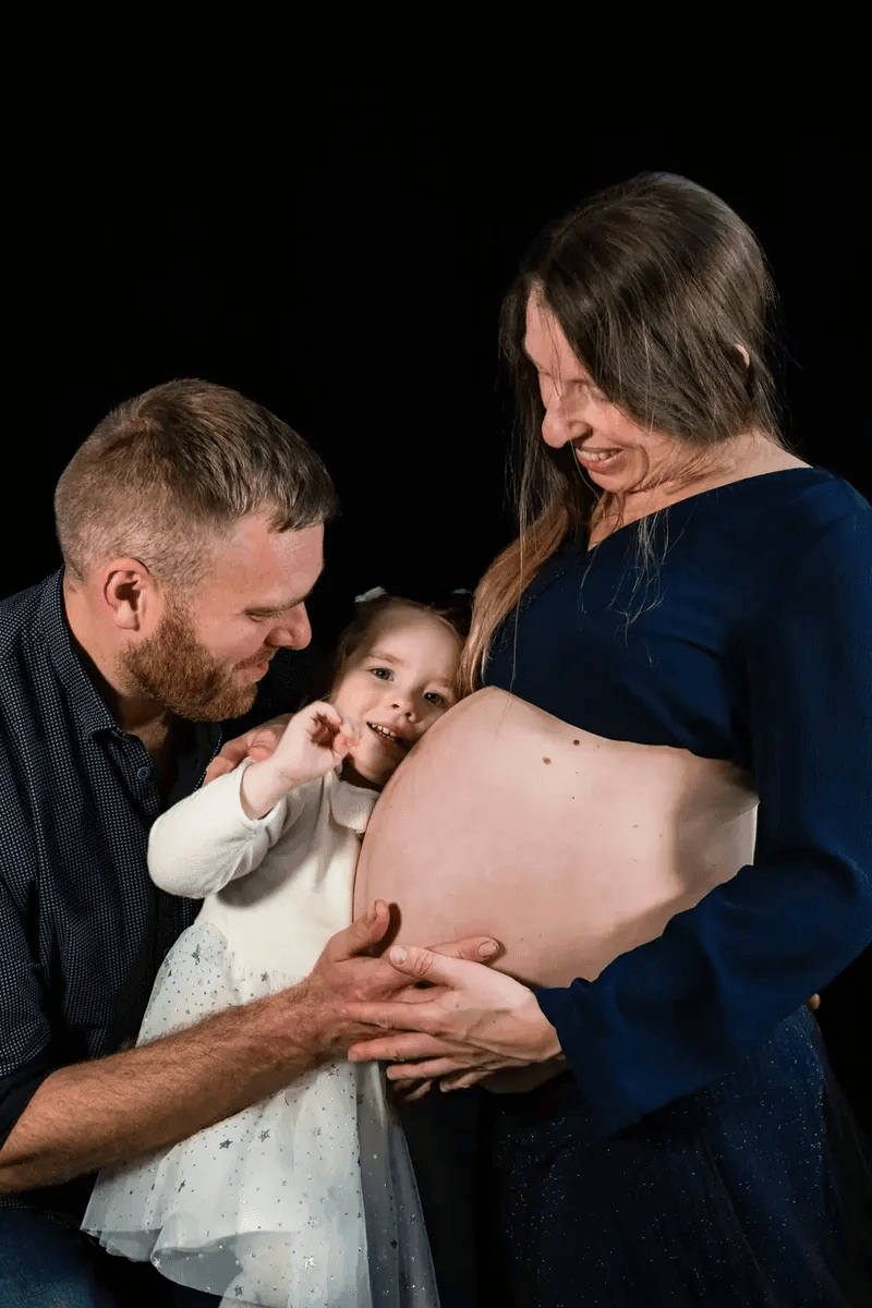 Famille regardant tendrement le ventre de la maman enceinte – séance grossesse