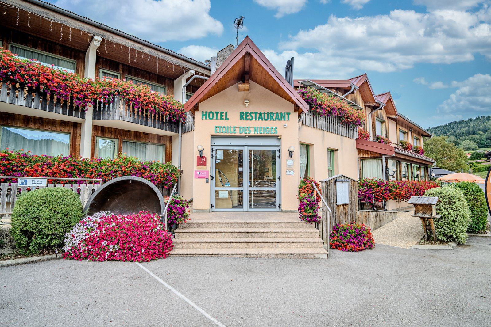Façade fleurie et entrée de l'Hôtel Étoile des Neiges à Métabief en été