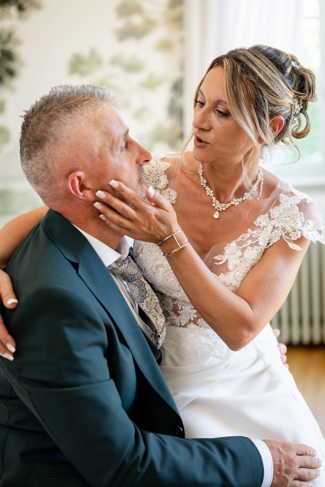La mariée caresse le visage du marié, moment complice avant la cérémonie