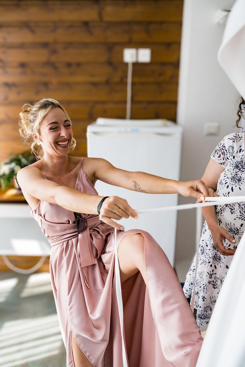 La témoin en robe rose tirant sur les lacets de la robe