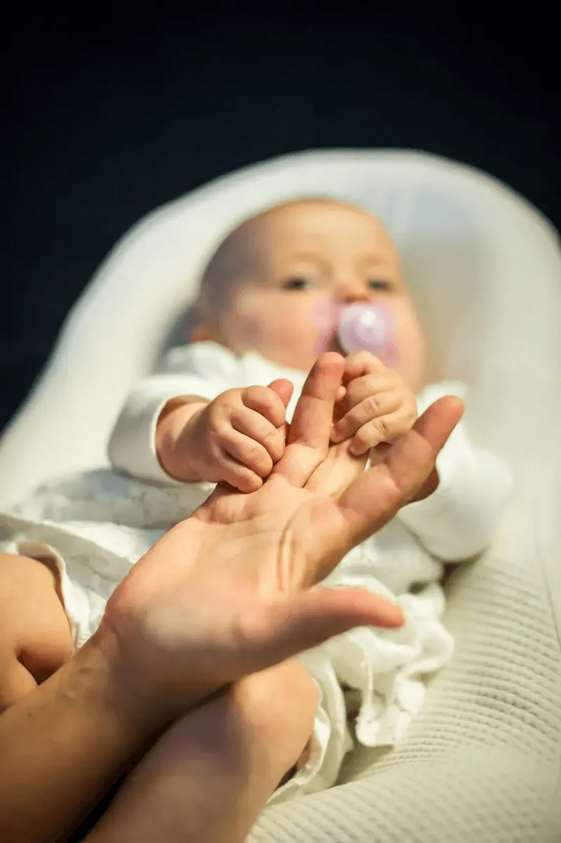 Le bébé tient les doigts de sa maman dans son cocon