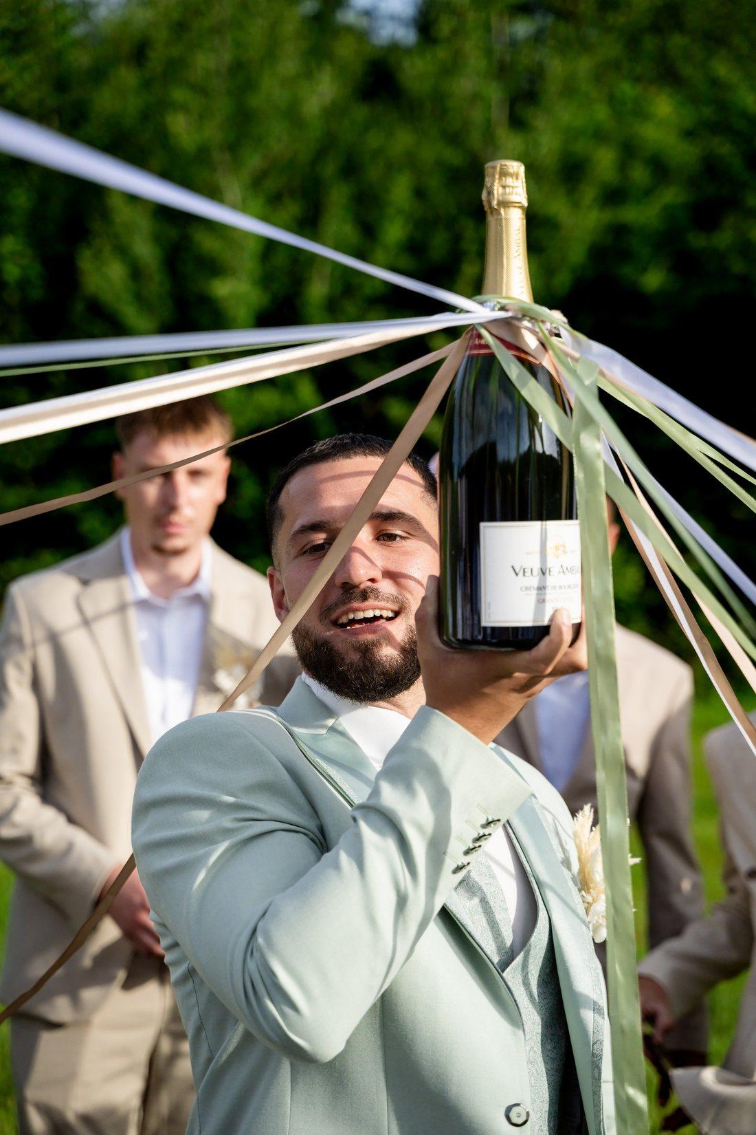 Le marié brandit un magnum de champagne au vin d'honneur