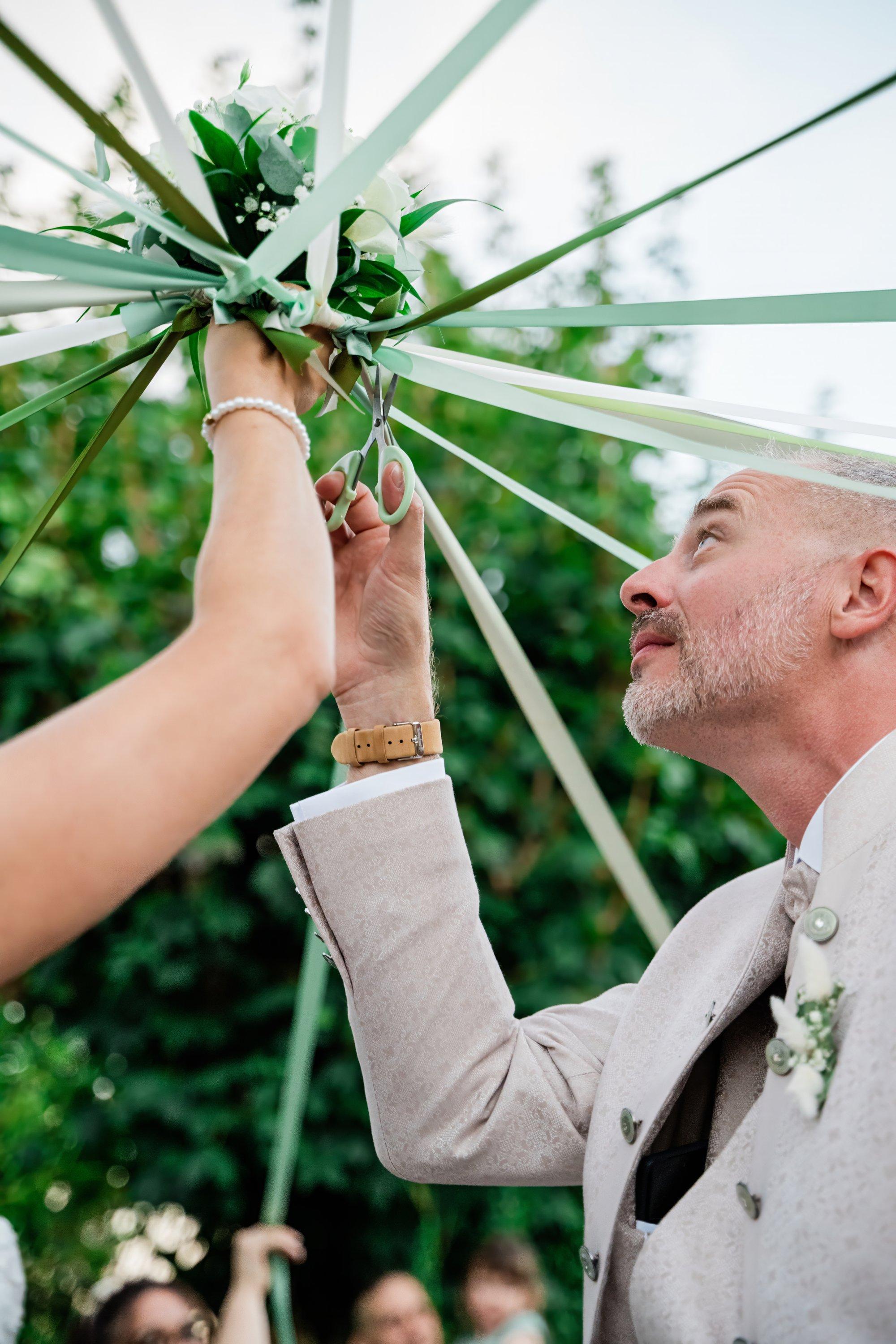 Le marié coupe les rubans du bouquet de la mariée