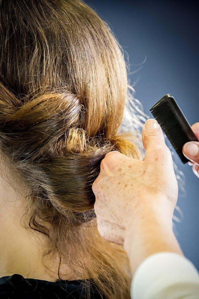 Mains d'une coiffeuse fixant une coiffure