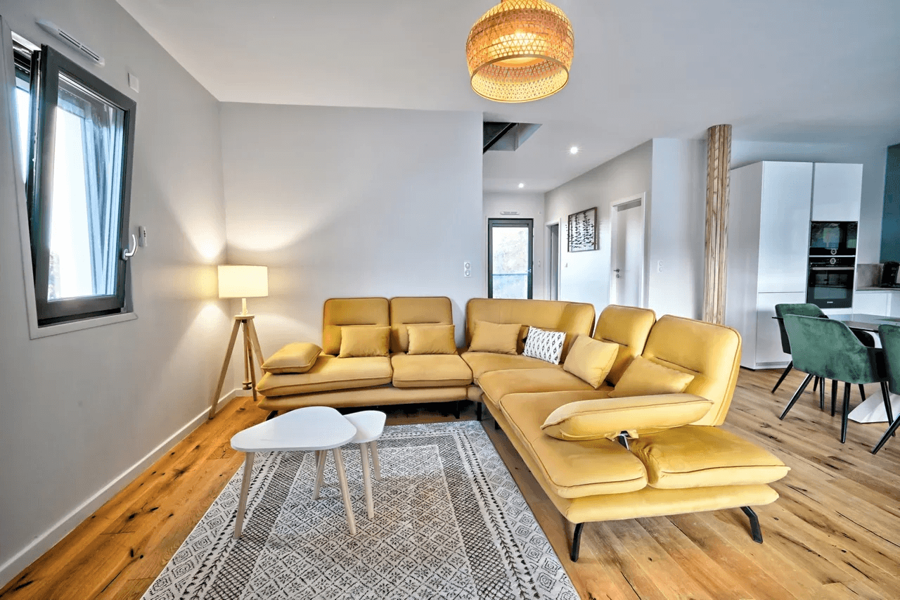 Salon moderne avec canapé jaune et grandes baies vitrées