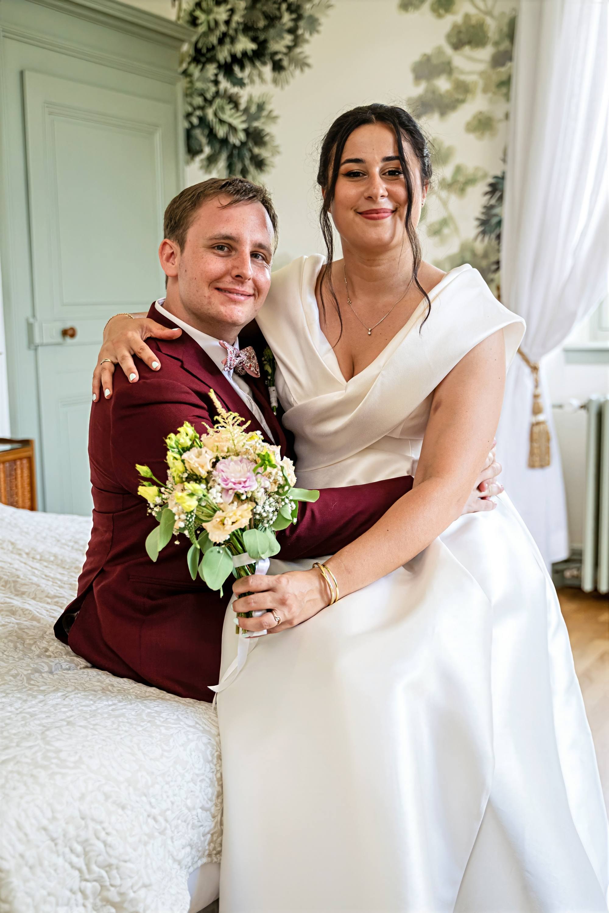 Portrait des mariés avec le bouquet dans une chambre de château
