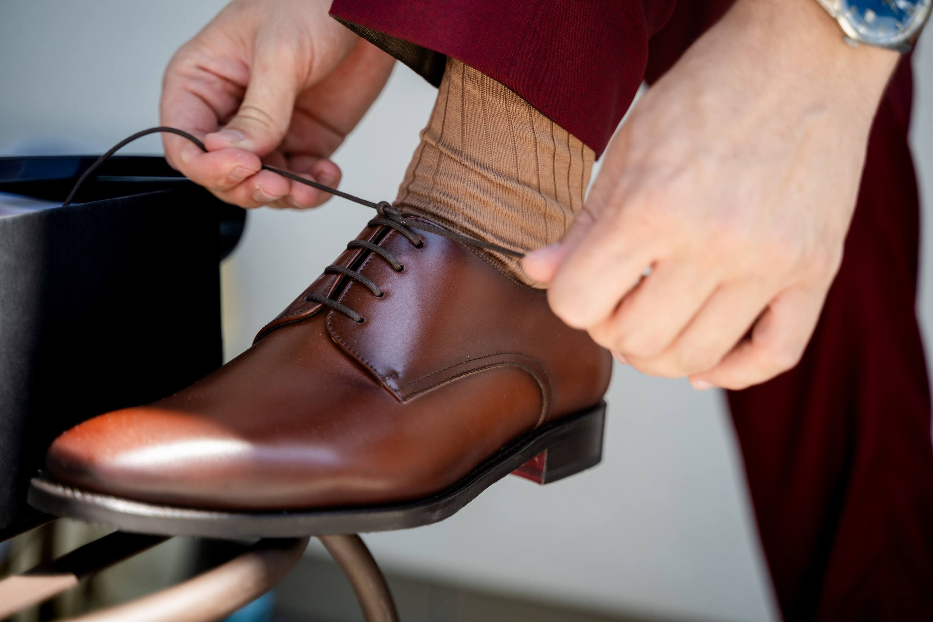 Le marié laçant ses chaussures en cuir pendant ses préparatifs