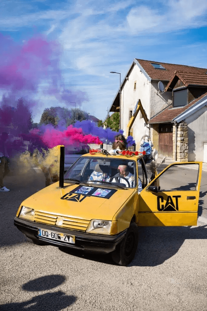 Voiture des mariés entourée de fumigènes colorés – animation festive mariage