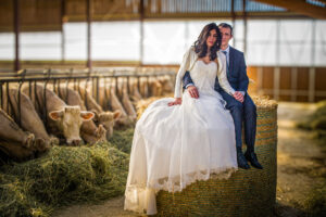 Les mariés assis sur une botte de foin dans une étable Couple de mariés assis sur une botte de foin dans une étable