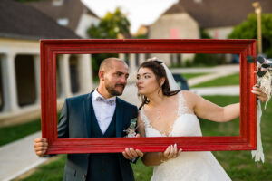 Les mariés posent derrière un cadre rouge près d'un lavoir Mariés posant derrière un cadre rouge près d'un lavoir