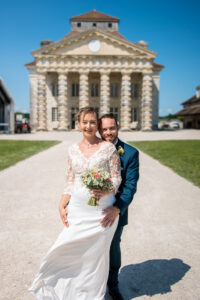 Les mariés posent devant les Salines d'Arc-et-Senans avec un bouquet Mariés posant avec un bouquet devant les Salines d'Arc-et-Senans