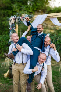 Les témoins du marié le portent en l'air pour une photo souvenir pendant le mariage Témoins soulevant le marié en l'air pour une photo souvenir pendant le mariage