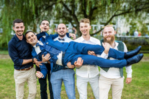 Les témoins portent le marié en riant Témoins portant le marié en riant lors de la cérémonie