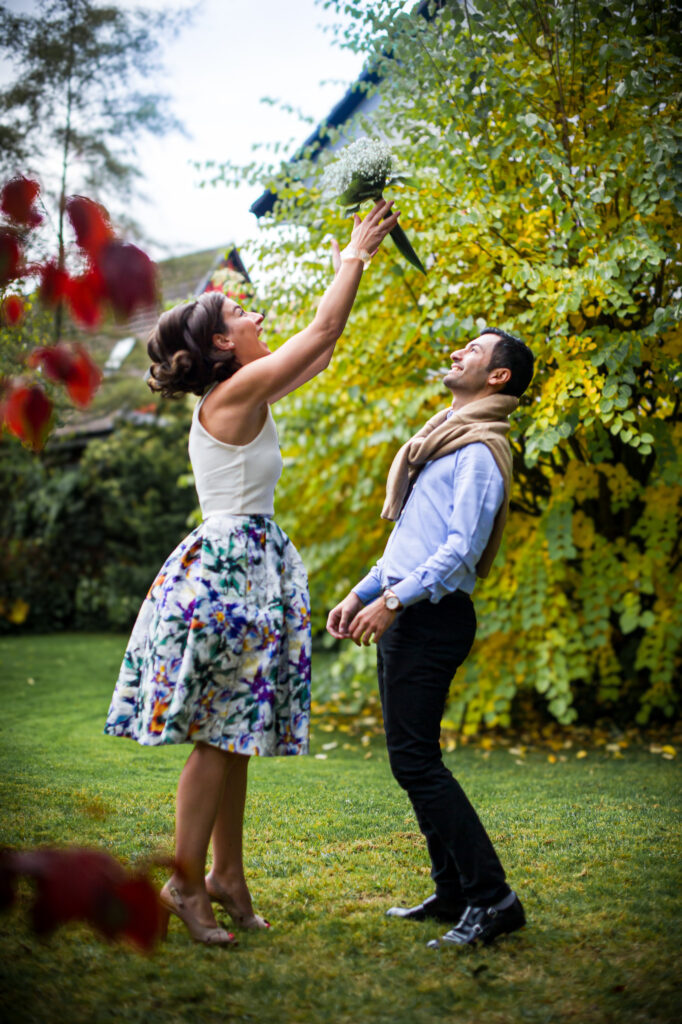 Love session : les futurs mariés s'amusent dans le jardin avec un bouquet de fleurs Futurs mariés s'amusant dans le jardin avec un bouquet de fleurs