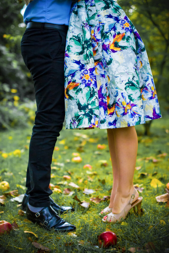 Love session : les jambes des futurs mariés dans le jardin avec des pommes par terre Jambes des futurs mariés dans le jardin avec des pommes par terre