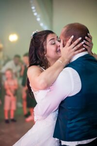 Marié et mariée s'embrassent lors de la soirée, mains sur la tête Embrassade tendre entre le marié et la mariée lors de la soirée