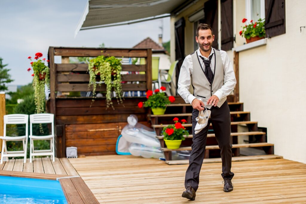 Le marié tenant les chaussures de la mariée près de la piscine lors d'une séance Trash the dress Marié tenant les chaussures de la mariée près de la piscine pendant une séance Trash the dress