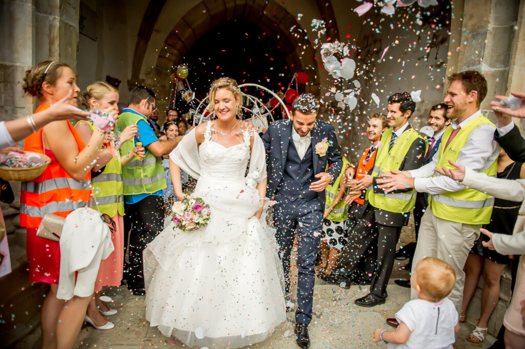 Les mariés sortant de l'église sous une pluie de confettis Mariés sortant de l'église sous des confettis