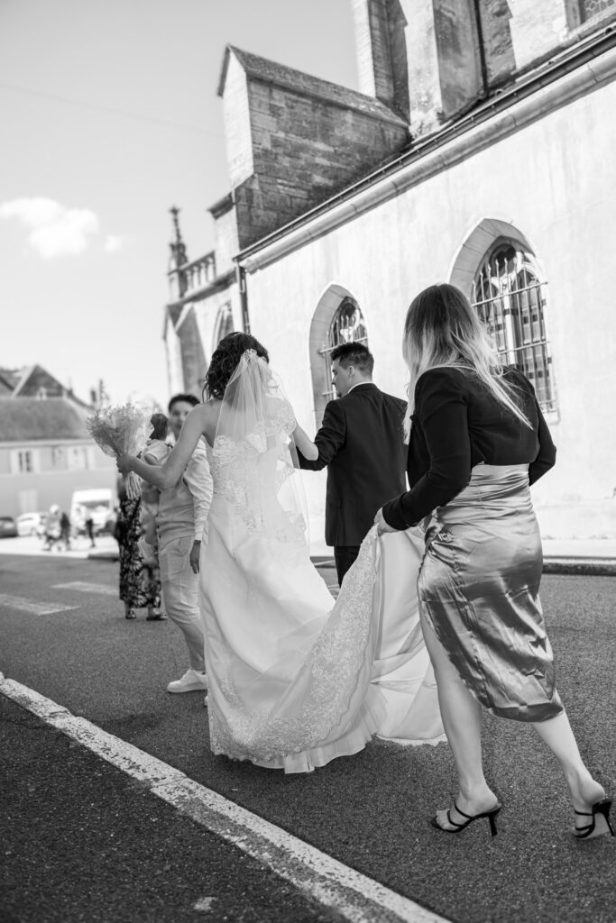 Une témoin aidant la mariée en tenant sa robe Témoin tenant la robe de la mariée pour l'aider
